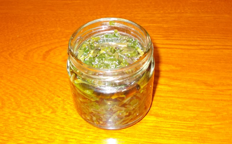 木のテーブルの上に置かれた、花わさびの醤油漬けが入ったガラス瓶。